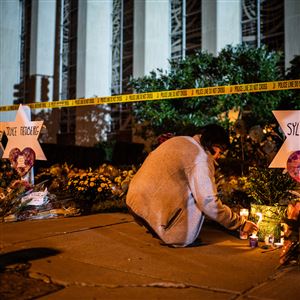 A woman leaves a candle in front of the Tree of Life synagogue in Squirrel Hill after a deadly attack there in October 2018. 