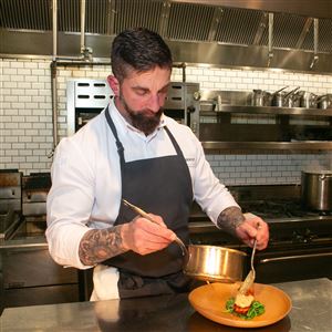Chef Dave Racicot spoons miso mustard sauce onto Fundy Bay salmon at The Commoner restaurant in Kimpton Hotel Monaco Pittsburgh.