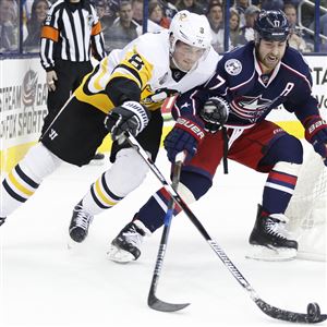 Penguins defenseman Brian Dumoulin chases a puck behind the net alongside Columbus Blue Jackets forward Brandon Dubinsky.