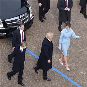President Donald Trump walks out of the car with his son Barron and wife Melania surrounded by Secret Service officers at the White House as the presidential inaugural parade winds through the nation's capital Friday afternoon.