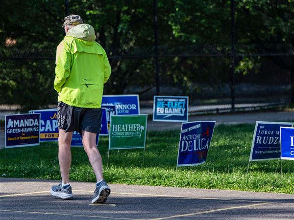 A man runs past election signs for candidates in the Pennsylvania primary Tuesday, May 20, 2025, at Linden Pre-K in Point Breeze.