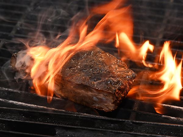 Pork ribs surrounded by fire on the grill at The Hyeholde Restaurant in Moon.