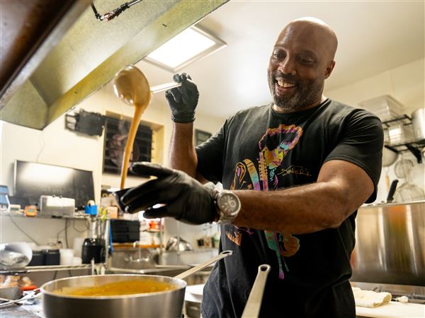 Chef LaShawn Espy prepares melted cheese for one of the Fry Bar Classicz, the Jerk.