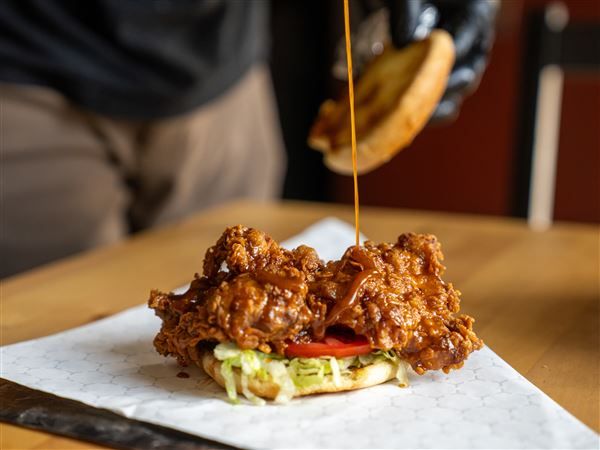 LaShawn Espy drizzles sauce onto one of the Fry Bar Sammichez, the Old Bay chicken.