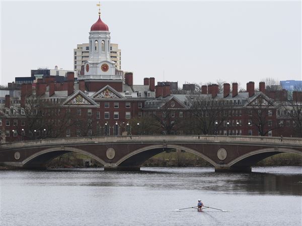 This file photo shows a sculler rowing down the Charles River near Harvard University, at rear, Tuesday, April 15, 2025, in Cambridge, Mass.