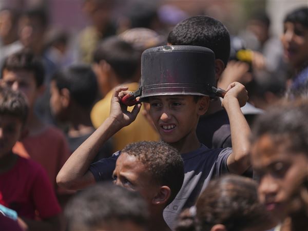 A young Palestinian waits to collect donated food at a food distribution kitchen in Deir al-Balah, Gaza Strip, Friday, May 30, 2025.