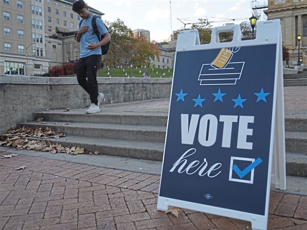 A voter places his ‘I voted sticker’ on his shirt passing a vote sign outside of the polling station at Soldiers and Sailors in Oakland Tuesday, Nov. 5, 2024.