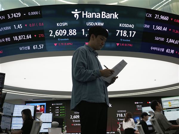 A currency trader works near a screen showing the Korea Composite Stock Price Index (KOSPI), top center left, and the foreign exchange rate between U.S. dollar and South Korean won, top center, at the foreign exchange dealing room of the KEB Hana Bank headquarters Thursday, May 22, 2025, in Seoul, South Korea.