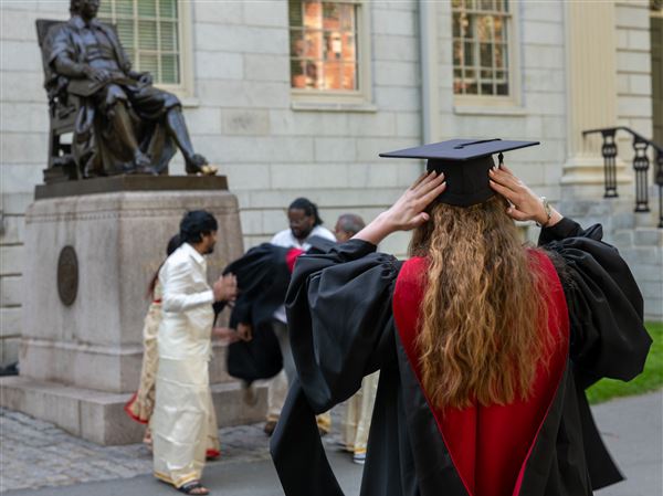 Graduation students, faculty and family gather in front of the statue of John Harvard in Harvard Yard on Wednesday in Cambridge, Mass. Harvard won a temporary victory on Thursday in a legal battle with the Trump administration over whether it can enroll international students, after a federal judge said that the university could continue to do so for now.