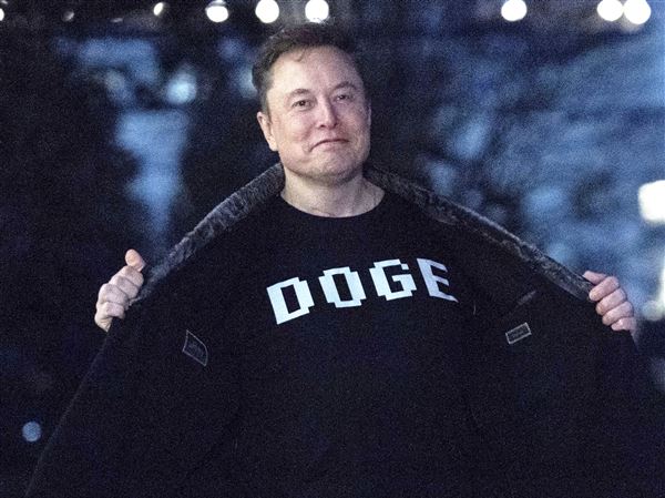 Elon Musk flashes his T-shirt that reads "DOGE" to the media as he walks on South Lawn of the White House, in Washington, March 9, 2025.
