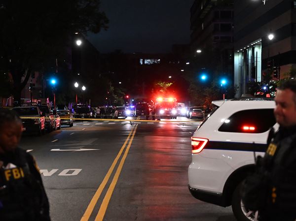 Emergency vehicles are seen in the distance as FBI agents guard the scene outside the Capital Jewish Museum following a shooting that left two people dead late Wednesday, May 21, 2025, in Washington.