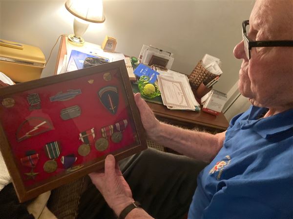 Tom Streicher, 99, of Cranberry looks at his medals  while reflecting on his time in the Army during World War II. 