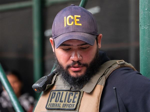 An ICE agent monitors hundreds of asylum seekers being processed upon entering the Jacob K. Javits Federal Building on June 6, 2023 in New York City.